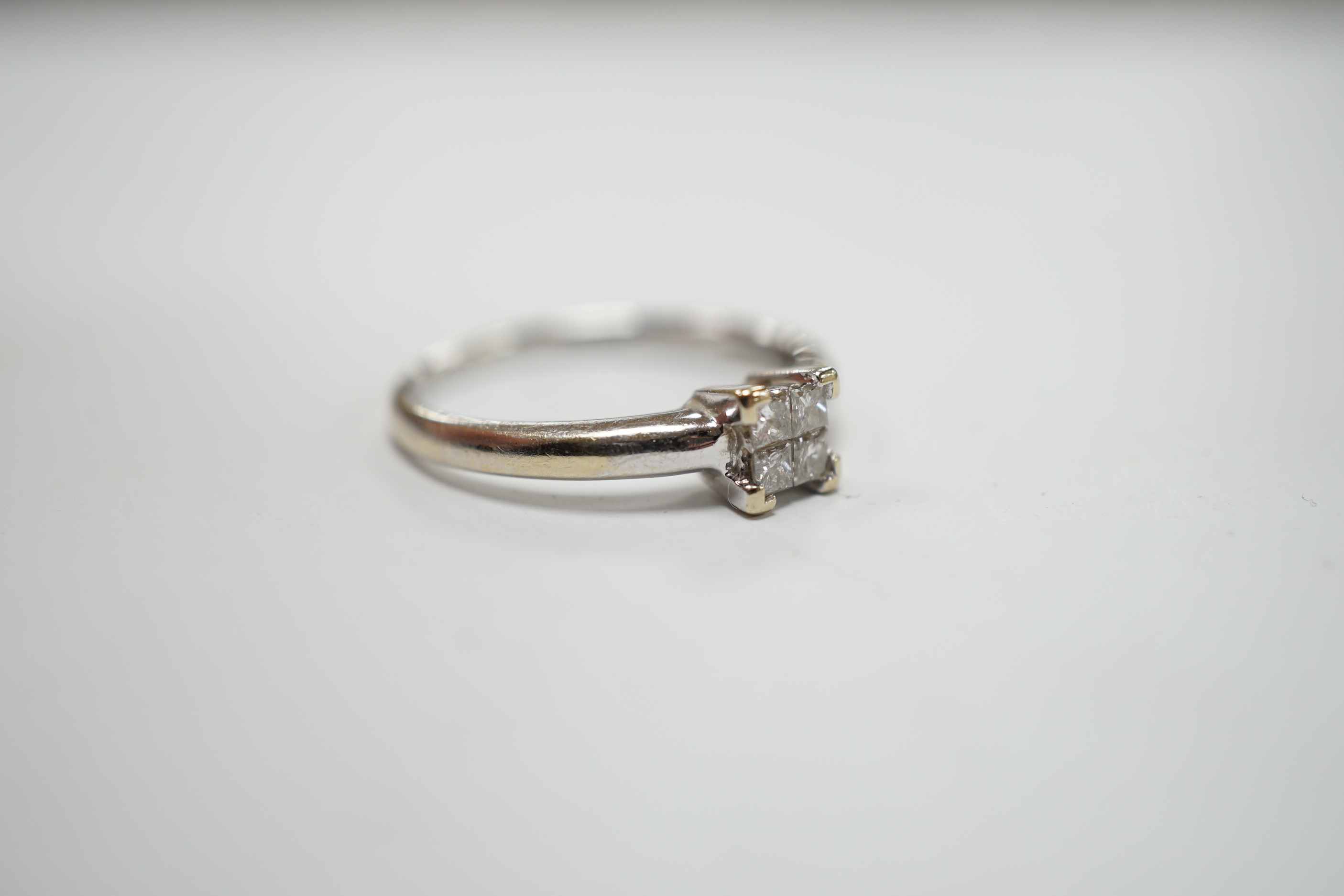 A modern 18ct white gold and four stone diamond set square cluster ring, size P/Q, gross weight 3.2 grams.